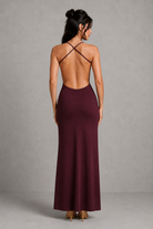Woman wearing a burgundy dress with thin straps against a gray background