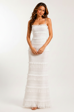 Woman wearing a white ruffled dress against a plain background