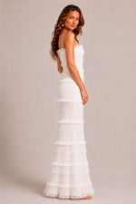Woman wearing a white tiered dress against a plain background