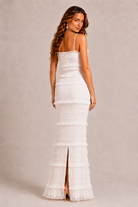 Woman wearing a white tiered dress on a plain background