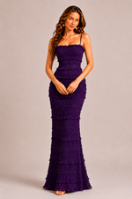 Woman wearing a purple evening gown against a plain background