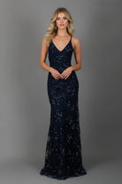 Woman wearing a navy blue sequin evening gown against a gray background