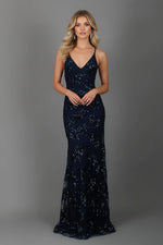 Woman wearing a navy blue sequin evening gown against a gray background