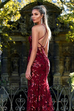 Woman in a red sequin dress standing in front of an ornate stone archway.