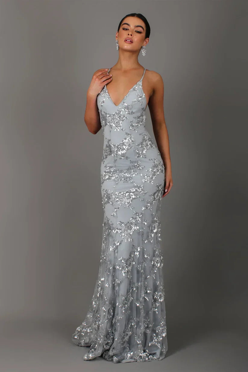 Woman wearing a silver sequin evening gown against a gray background