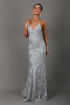 Woman wearing a silver sequin evening gown against a gray background