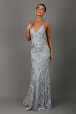 Woman wearing a silver sequin evening gown against a gray background