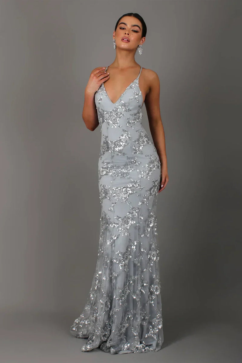 Woman wearing a silver sequin evening gown against a gray background