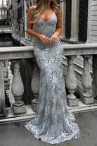 Woman in a silver sequin dress standing on a balcony with a cityscape background