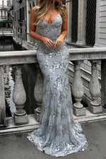 Woman in a silver sequin dress standing on a balcony with a cityscape background