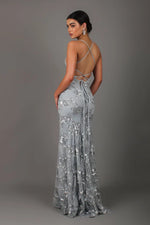 Woman wearing a silver sequin gown against a gray background