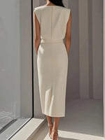 Woman wearing a white dress standing in a minimalistic room with a large window.