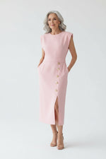 Pink dress with gold buttons worn by a person in a minimalistic setting