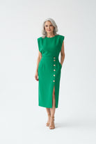Woman wearing a green dress with buttons standing in a modern interior setting.
