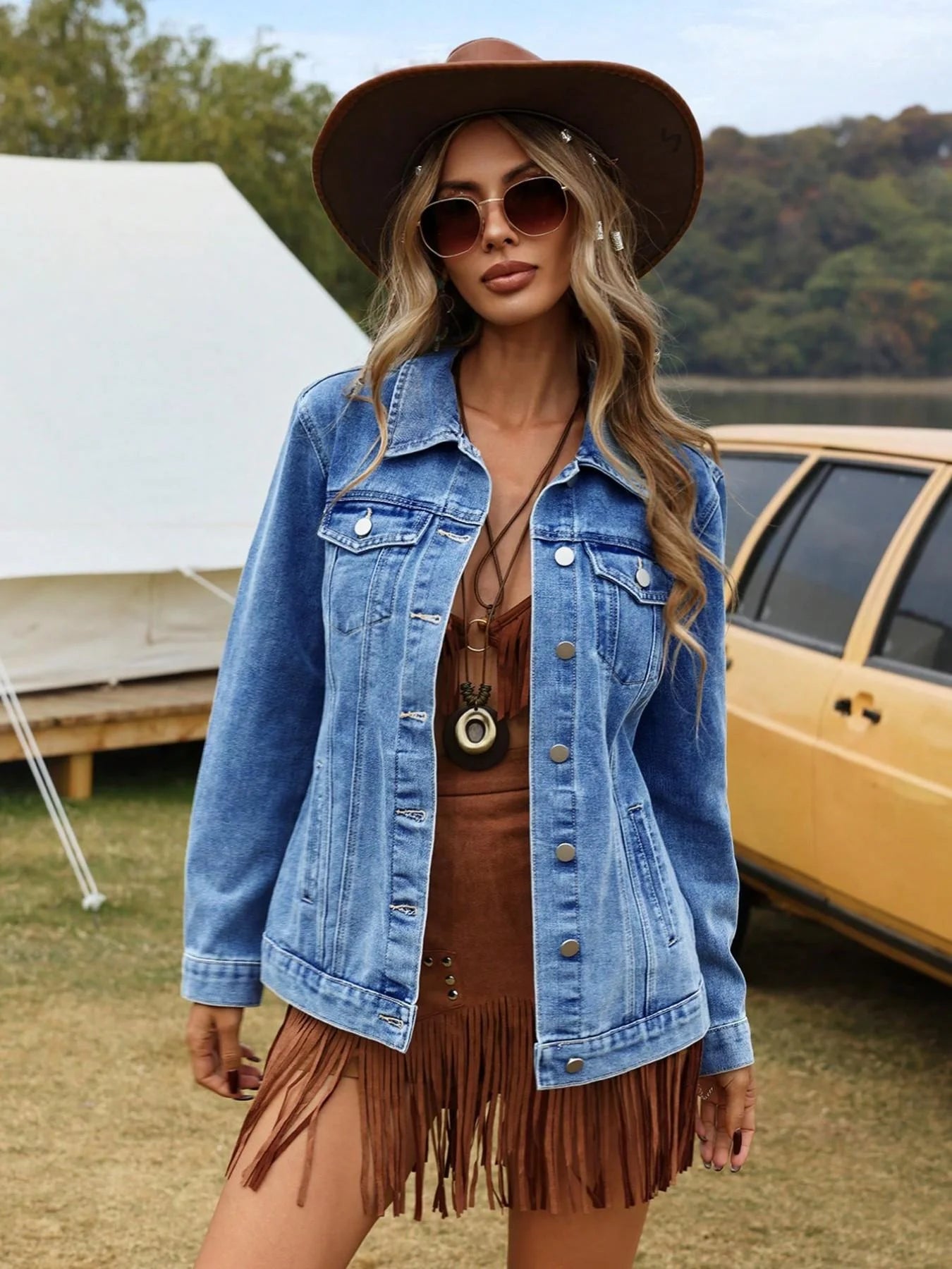 Woman wearing a denim jacket and brown hat outdoors with a tent and vehicle in the background