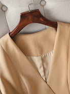 Beige coat on a wooden hanger against a neutral background