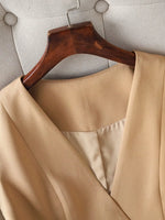 Beige coat on a wooden hanger against a neutral background