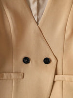 Close-up of a beige trench coat with black buttons