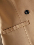 Close-up of a beige coat with a button and lapel detail