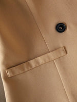 Close-up of a beige coat with a button and lapel detail