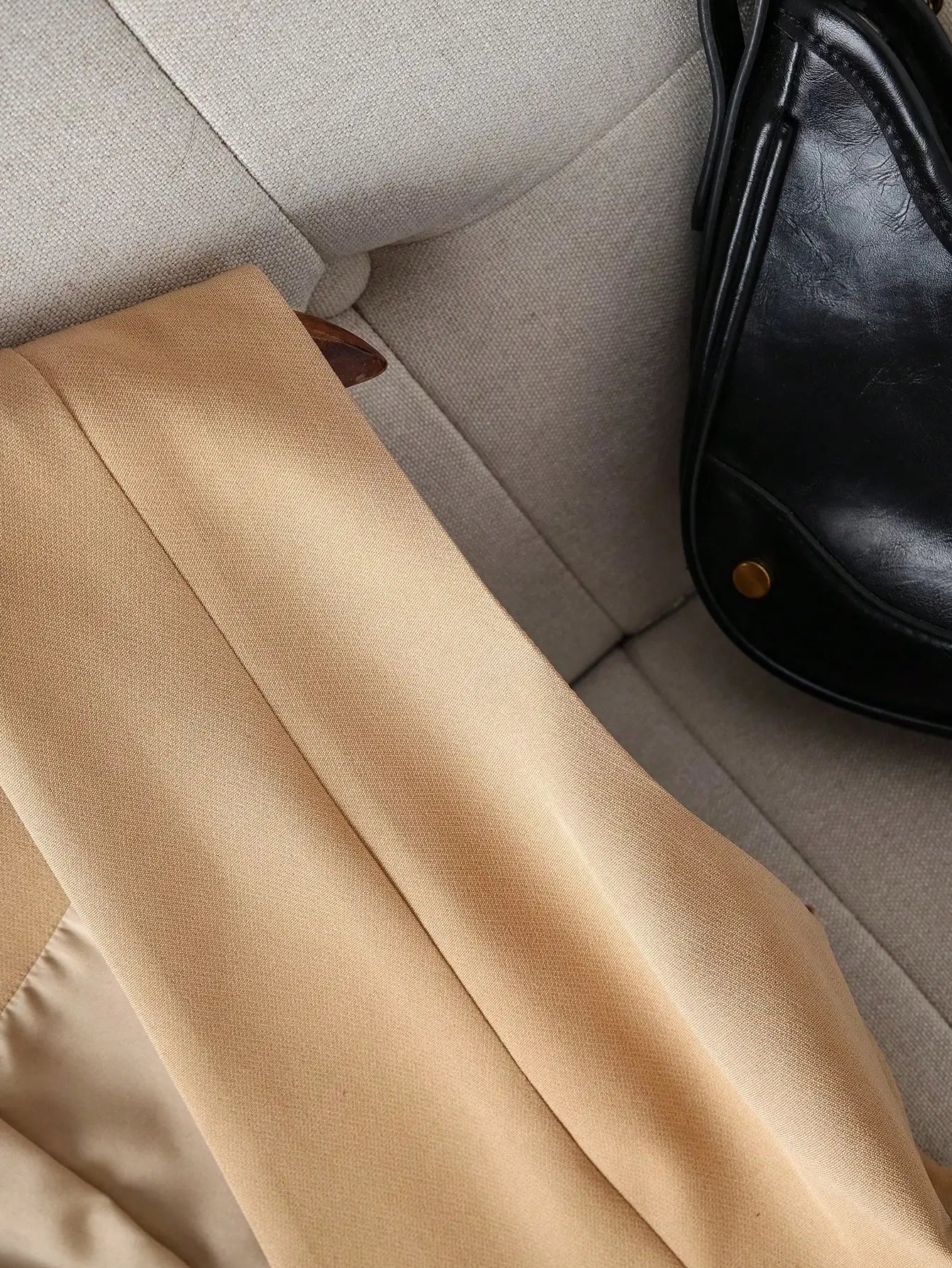Beige pants on a light gray couch with a black bag beside them