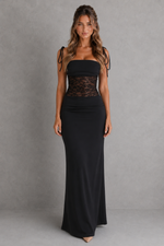 Woman wearing a black strapless gown with lace detailing against a gray background