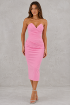 Woman wearing a pink strapless dress against a gray background