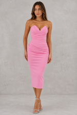Woman wearing a pink strapless dress against a gray background