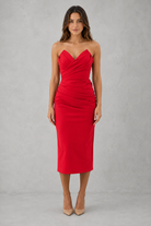 Woman wearing a red strapless dress against a gray background