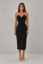 Woman wearing a black strapless dress against a gray background