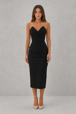 Woman wearing a black strapless dress against a gray background