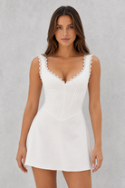 Woman wearing a white dress with lace details on a gray background