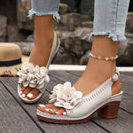 White sandals with floral designs on a wooden floor