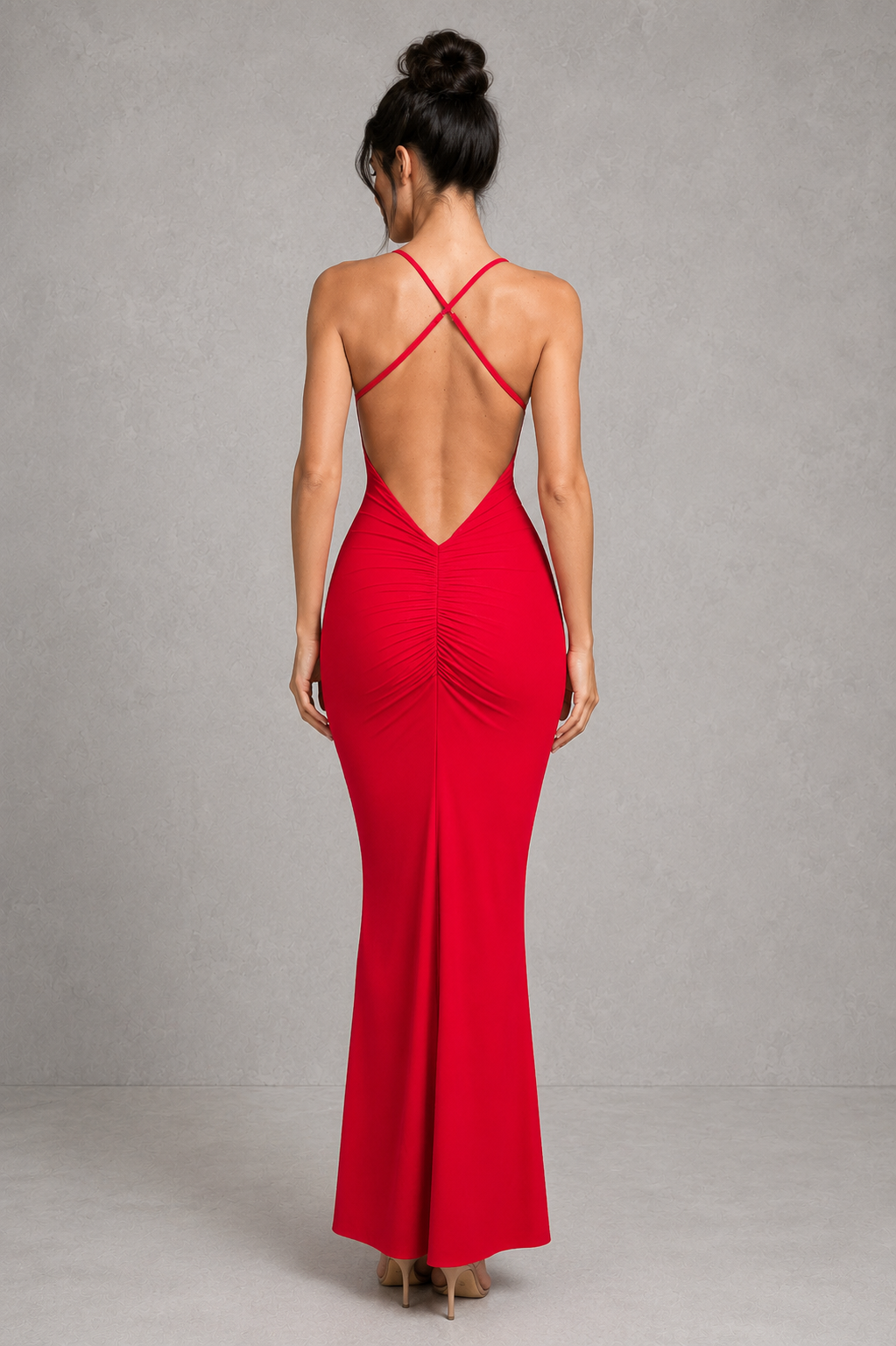 Woman wearing a red evening gown with a backless design on a gray background