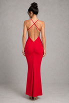 Woman wearing a red evening gown with a backless design on a gray background