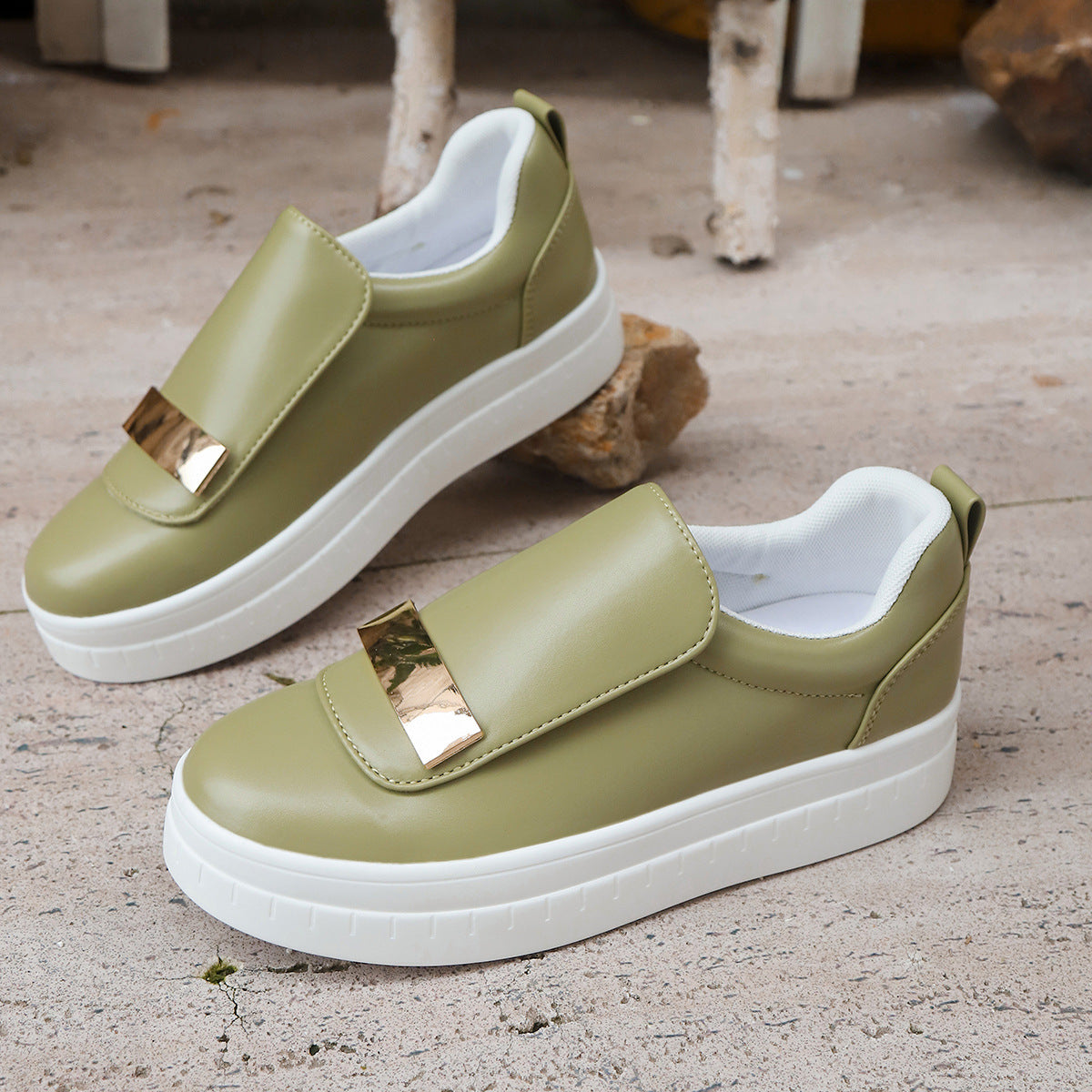 Green slip-on shoes with gold accents on a textured surface