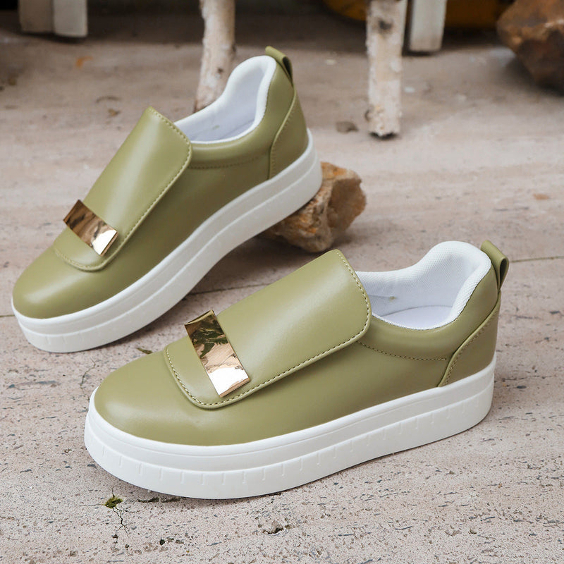 Green slip-on shoes with gold accents on a textured surface