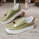 Green slip-on shoes with gold accents on a textured surface