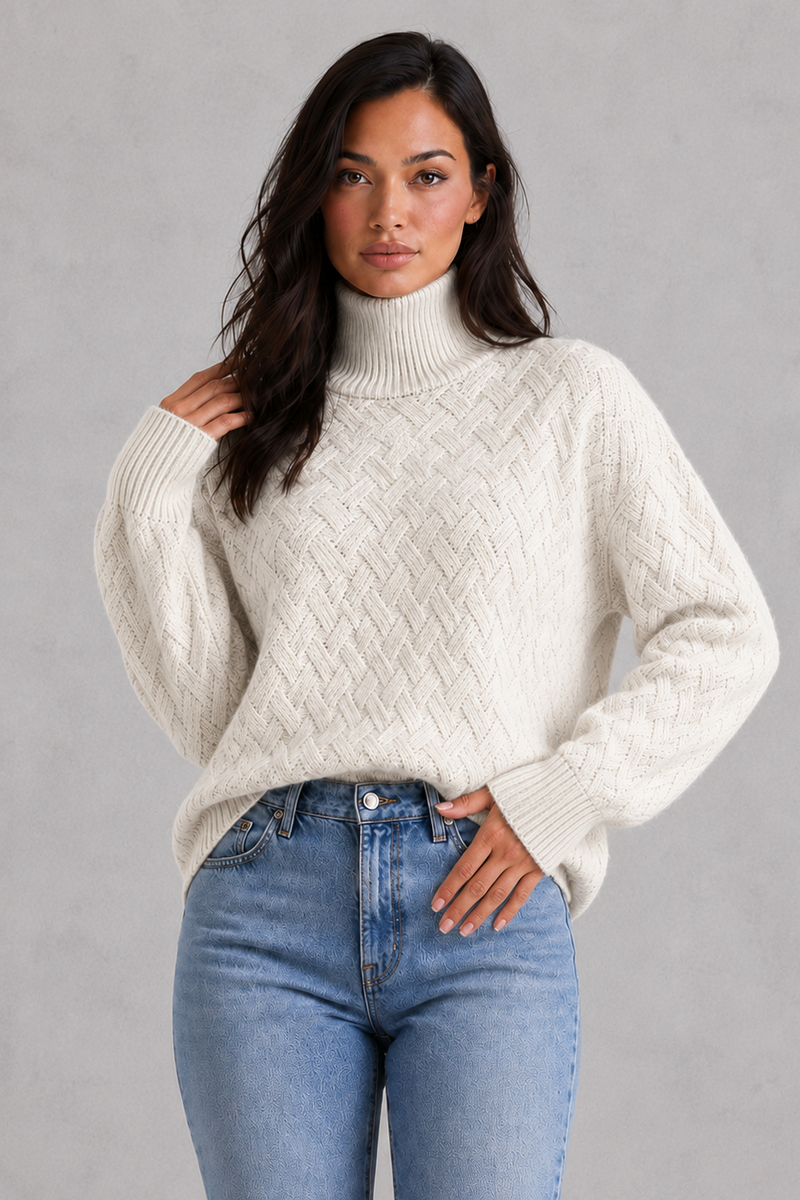 Woman wearing a cream sweater and blue jeans against a gray background