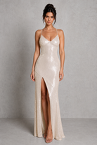 Woman wearing a long, elegant dress with a high slit on a plain background