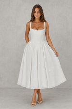 Woman wearing a white dress against a gray background