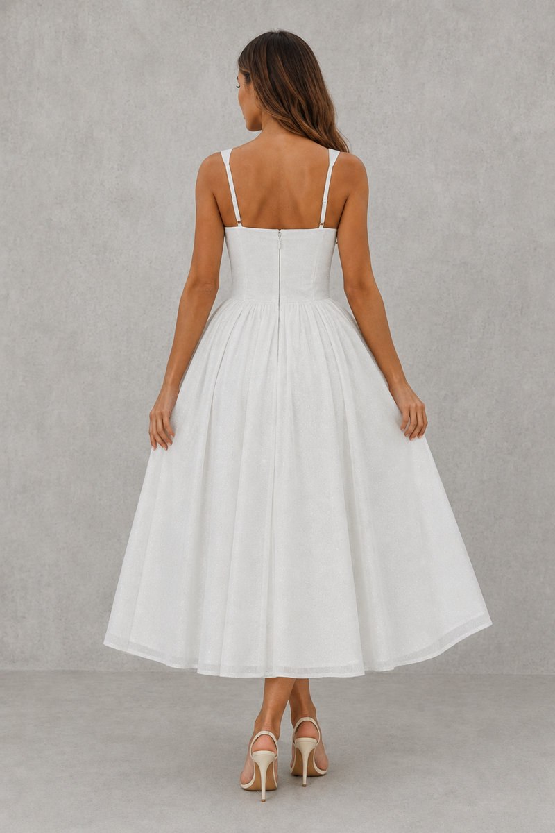 Woman wearing a white dress with thin straps against a gray background