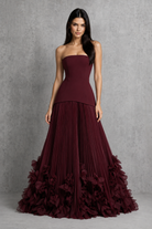 Women’s cherry lacquer strapless corset gown with a lace-up back, pleated full skirt, and handcrafted floral appliqué hem