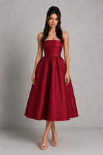 Woman wearing a red strapless dress against a gray background