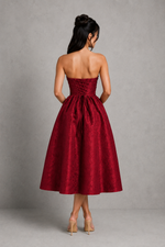 Woman wearing a strapless red dress against a gray background