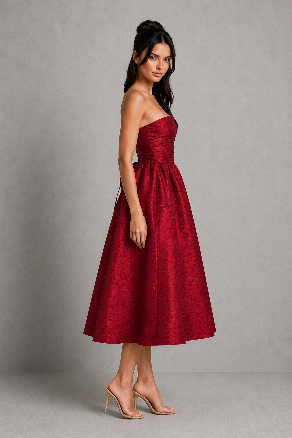 Woman wearing a red strapless dress against a gray background
