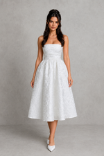 Woman wearing a white strapless dress against a gray background