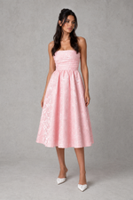 Woman wearing a pink strapless dress against a gray background