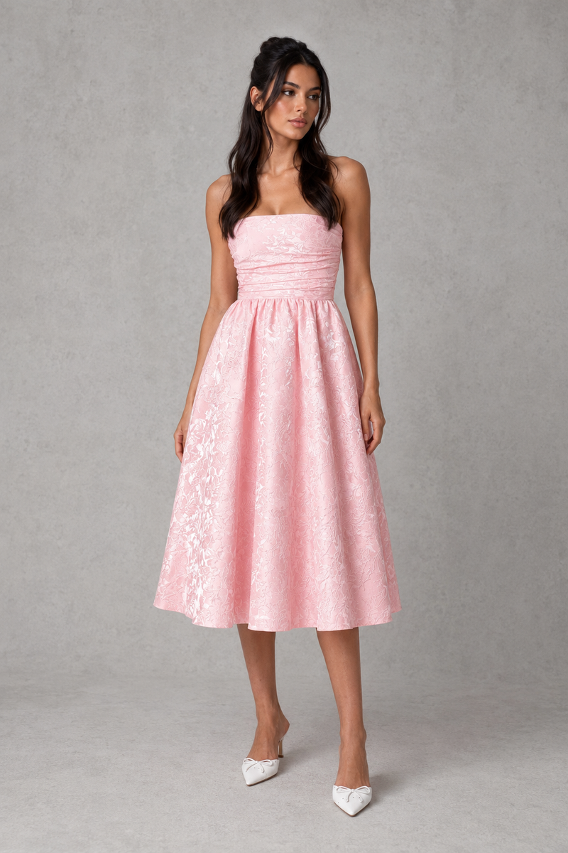 Woman wearing a pink strapless dress against a gray background