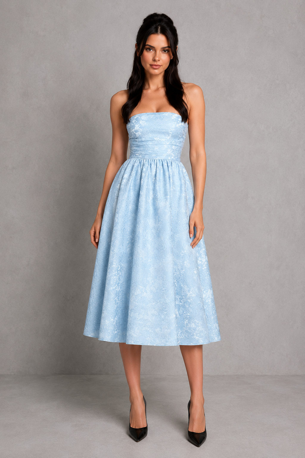 Woman wearing a light blue strapless dress against a gray background